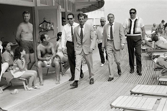 'Frank Sinatra on the boardwalk at Miami Beach Florida, accompanied by stand-in and bodyguards, 1968